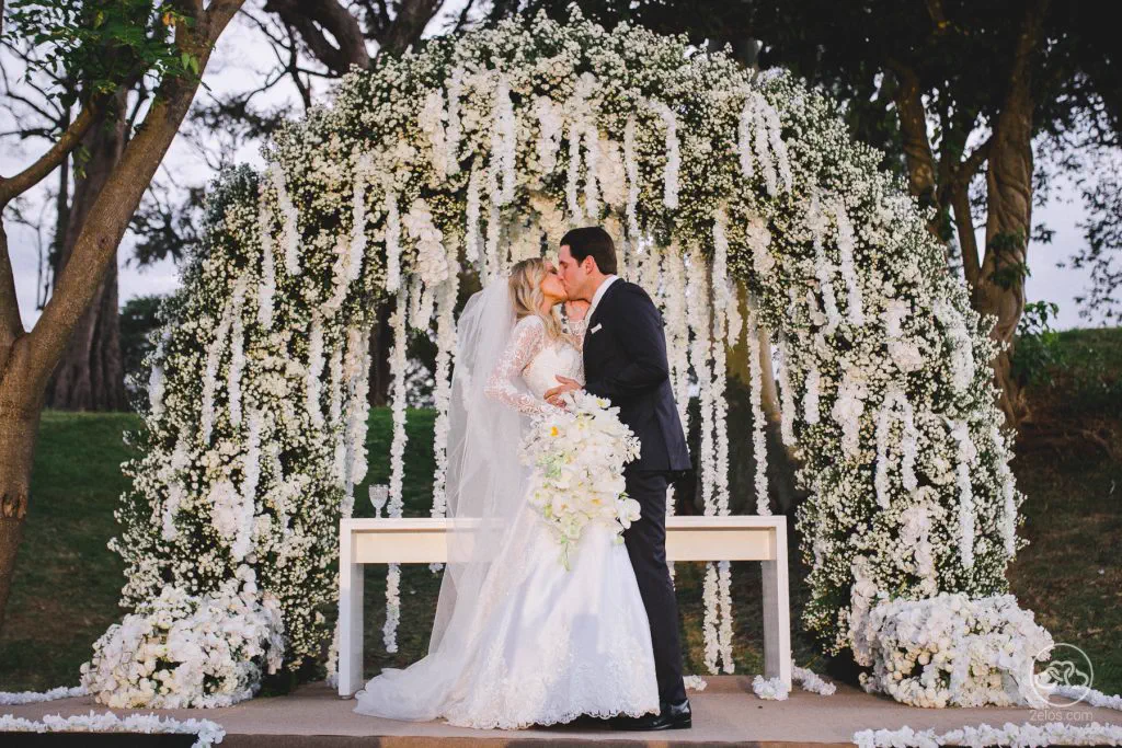 Noivos sob arco de flores em casamento ao ar livre